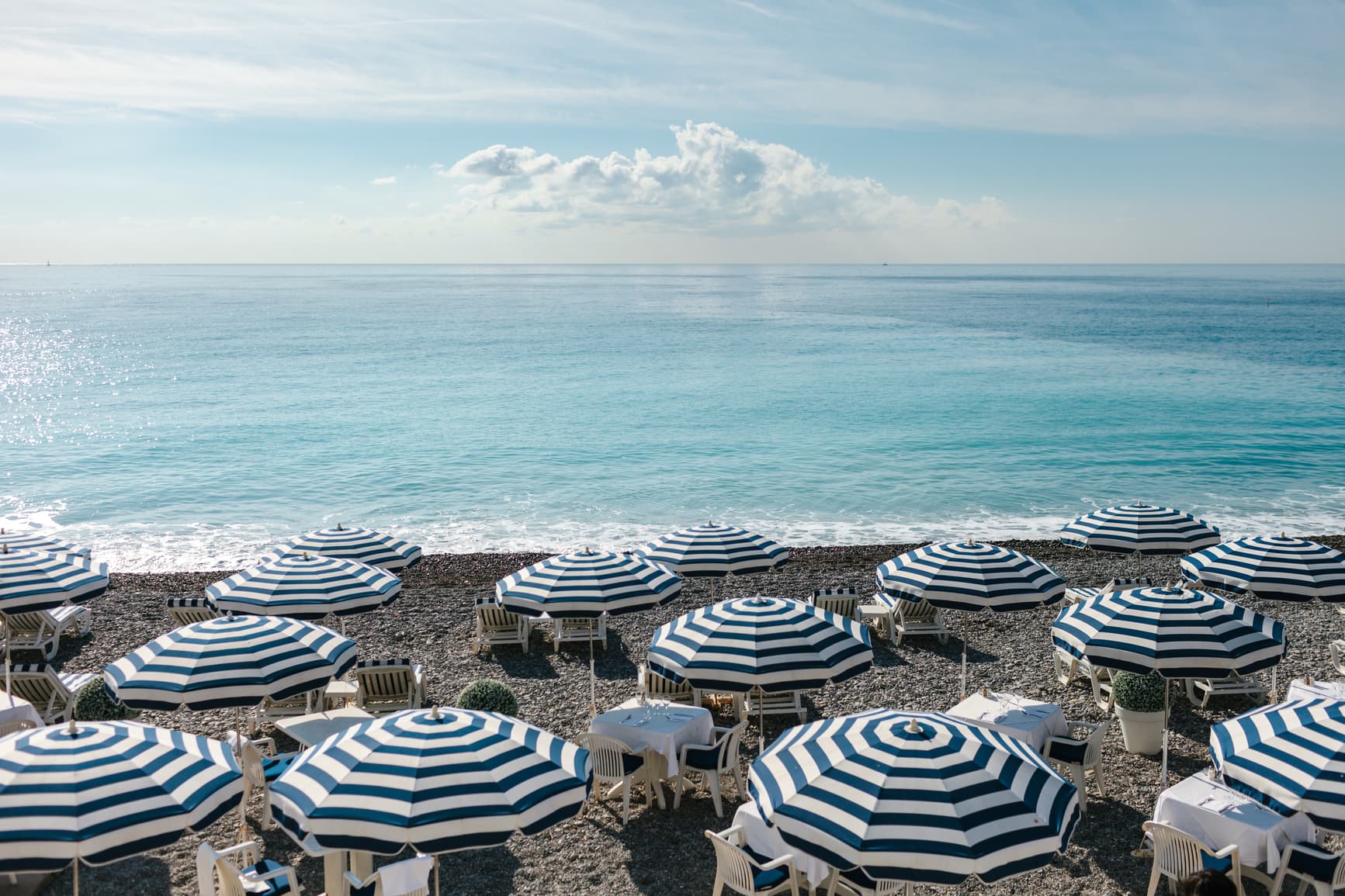 Stocksy image of a beach with striped lounge umbrellas dotting the shore